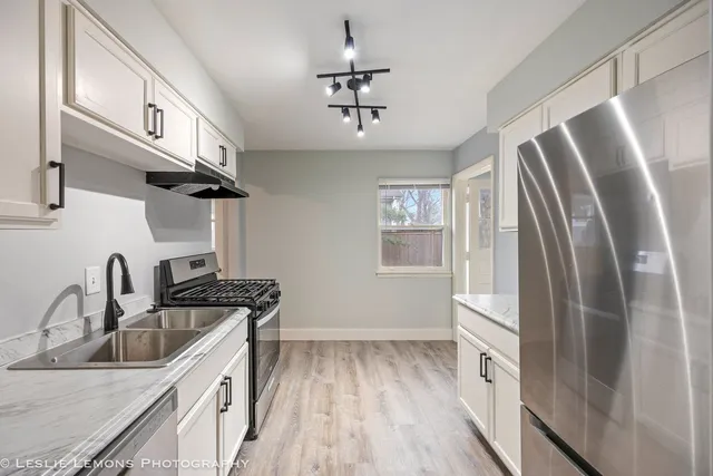 a kitchen with stainless steel appliances granite countertop a sink refrigerator and cabinets