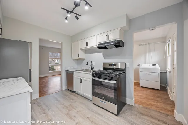 a kitchen with stainless steel appliances a stove a sink and white cabinets