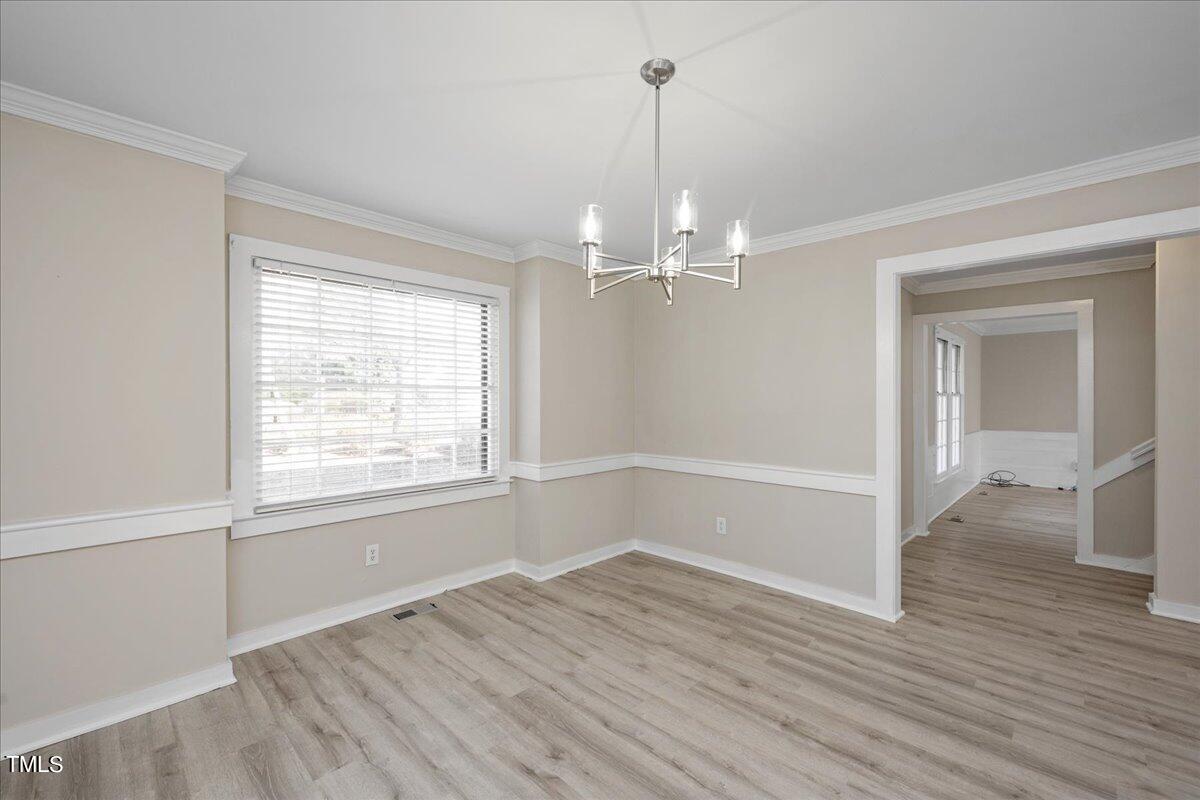 2205 Pastille Lane Raleigh, NC 27612 - Photo 11 of 31 an empty room with wooden floor mirror and windows
