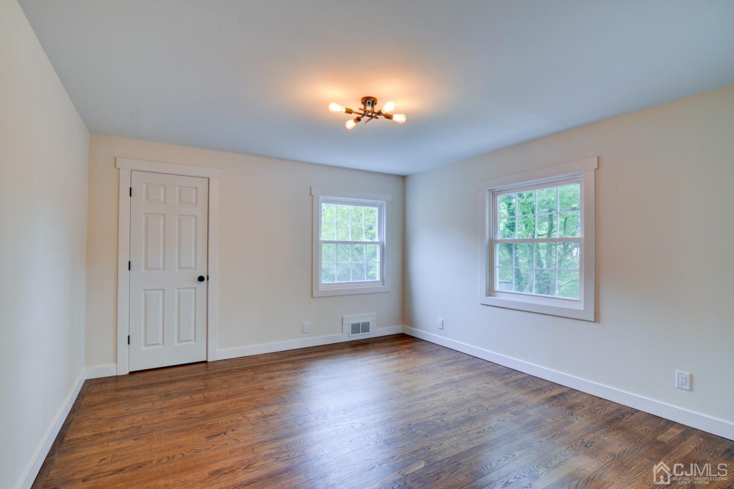 420 Chain O' Hills Road Colonia, NJ 07067 - Photo 15 of 37 an empty room with wooden floor chandelier and windows