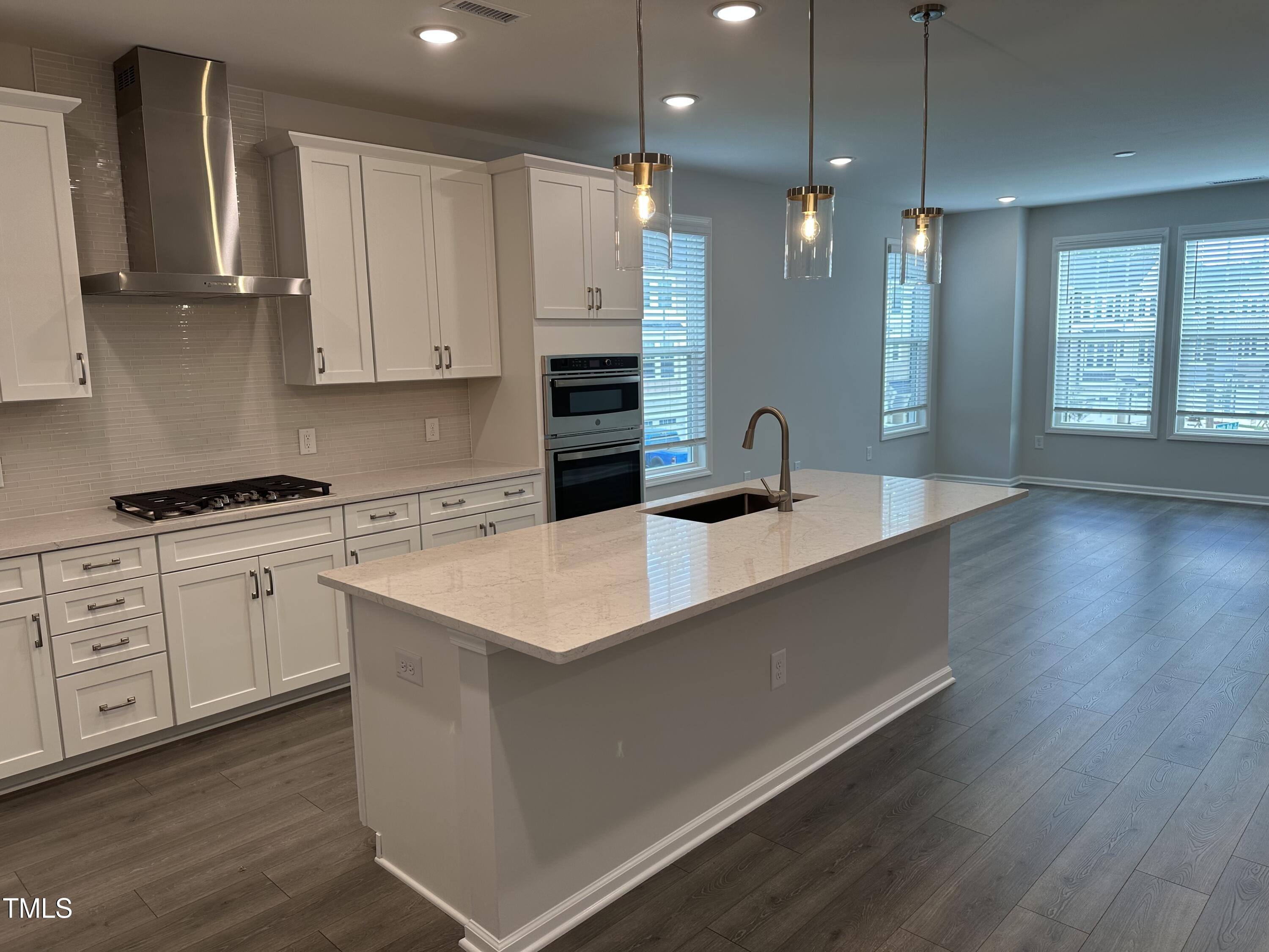 2209 Lambert Road Cary, NC 27519 - Photo 9 of 51 a kitchen with white cabinets a sink dishwasher and a stove with wooden floor