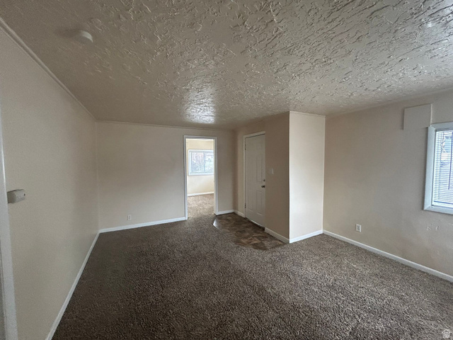 265 Rigdon Avenue, Unit 1 Salt Lake City, UT 84115 - Photo 15 of 15 Carpeted living area featuring light-toned walls, white trim, and a textured ceiling
