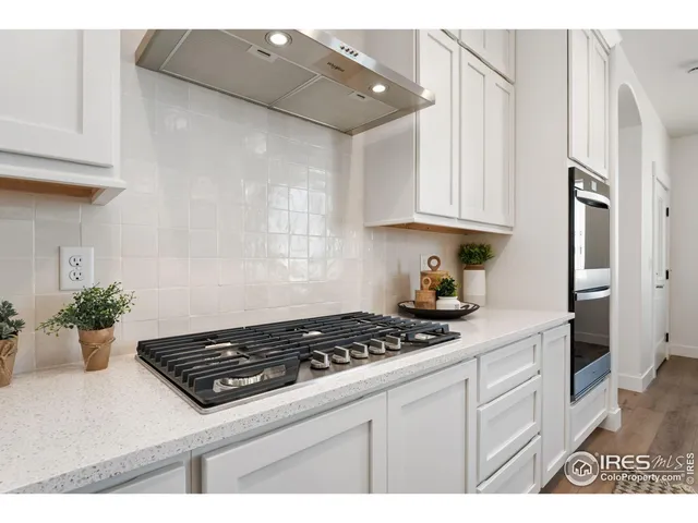 a kitchen with white cabinets and stove