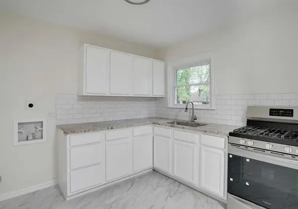 a kitchen with white cabinets sink and appliances