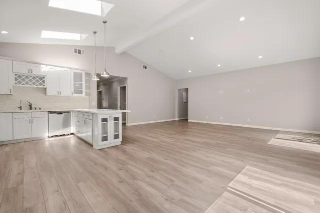 a view of kitchen with stainless steel appliances refrigerator oven and white cabinets with wooden floor