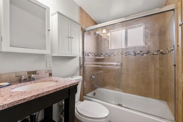 a bathroom with a granite countertop sink toilet and shower