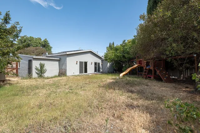 a view of a house with backyard and trees