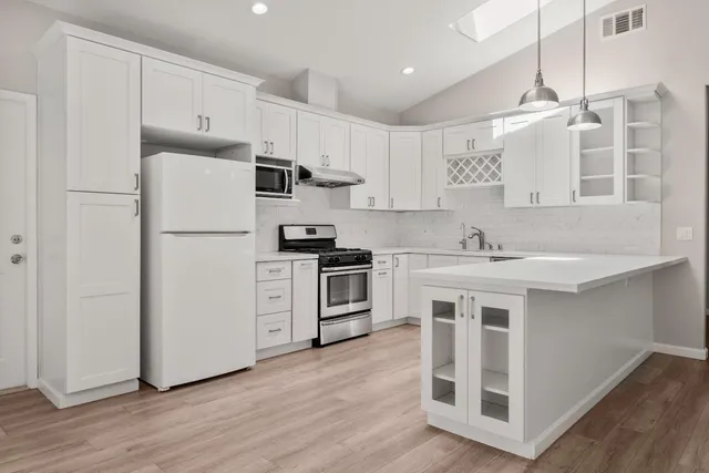 a kitchen with white cabinets and stainless steel appliances