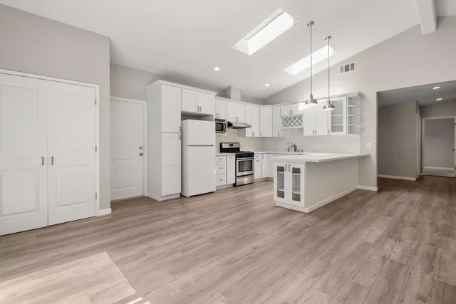 a view of kitchen with stainless steel appliances refrigerator stove microwave and cabinets