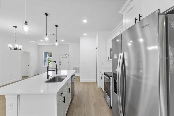 a kitchen with stainless steel appliances a stove a refrigerator a sink a chimney wooden floor and cabinets
