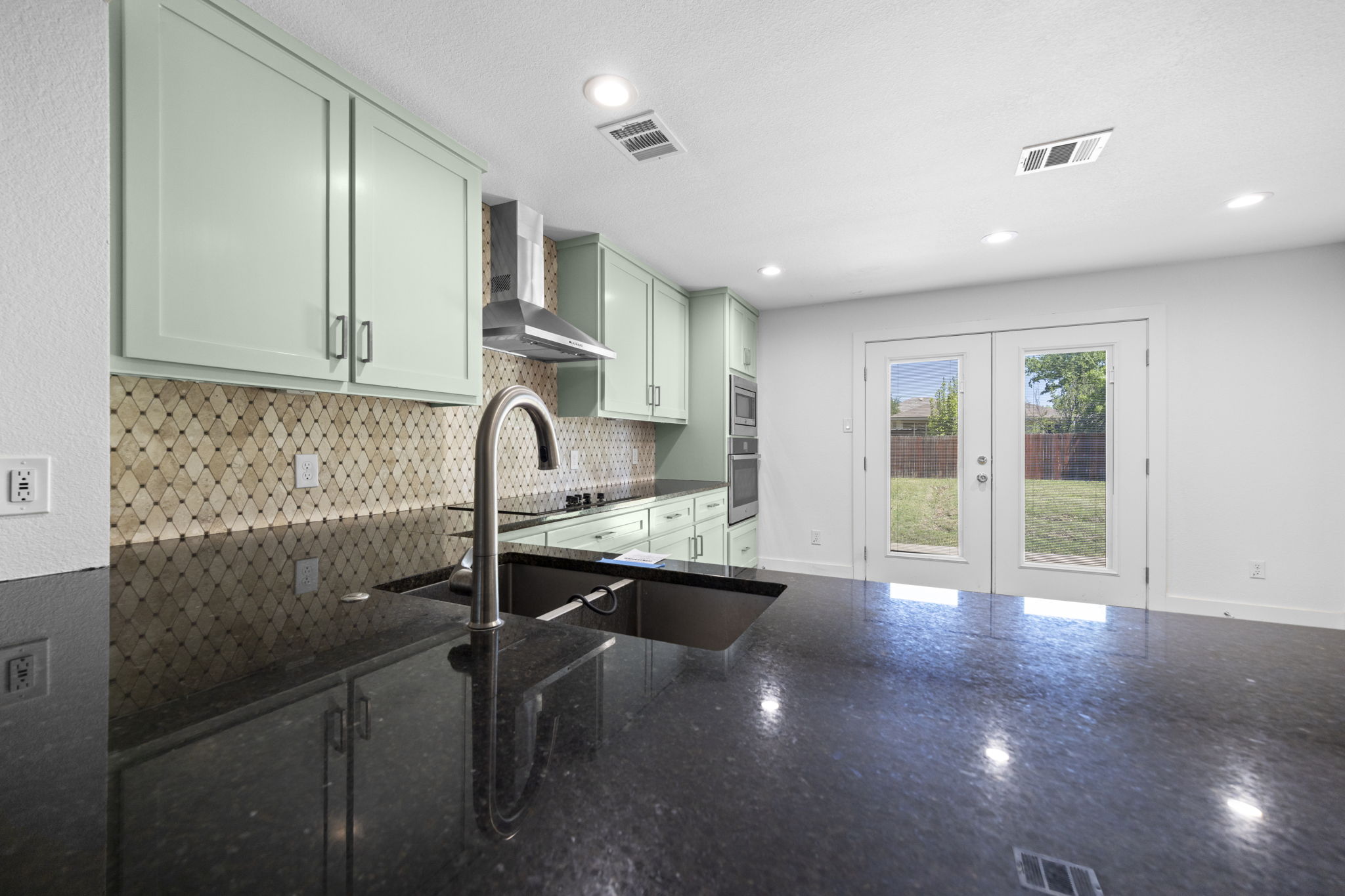 89 Jan Lane Georgetown, TX 78626 - Photo 8 of 29 Kitchen featuring green cabinets, dark stone counters, french doors, decorative backsplash, and stainless steel appliances
