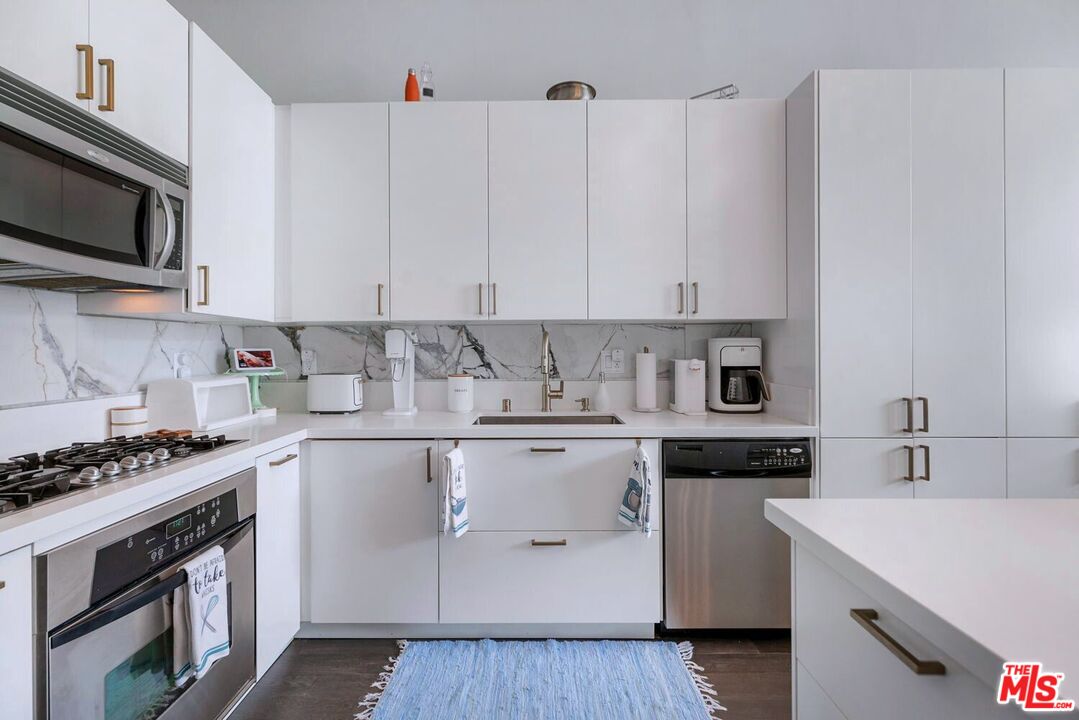 645 West 9th Street, Unit 740 Los Angeles, CA 90015 - Photo 17 of 63 a kitchen with stainless steel appliances granite countertop a stove top oven a sink dishwasher and white cabinets