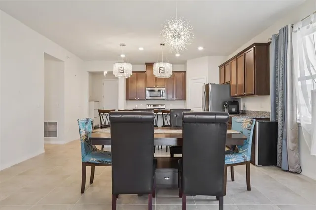 a living room with stainless steel appliances furniture a dining table and kitchen view