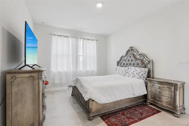 a bedroom with a bed and a flat tv screen on the dresser