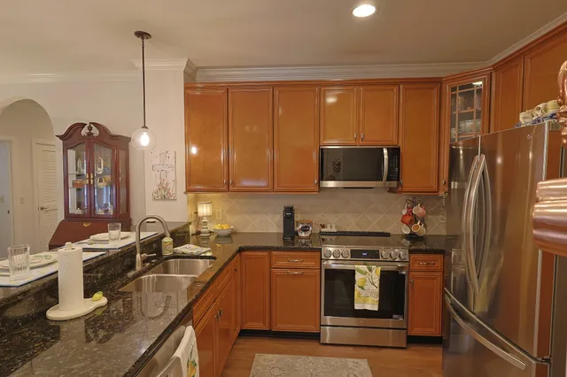 a kitchen with stainless steel appliances granite countertop a sink a stove and a refrigerator