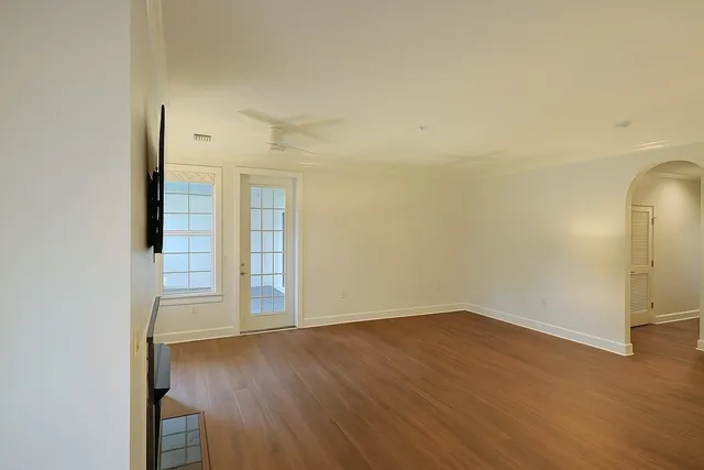 an empty room with wooden floor and windows