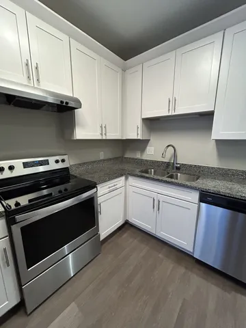 a white kitchen with granite top and stainless steel appliances