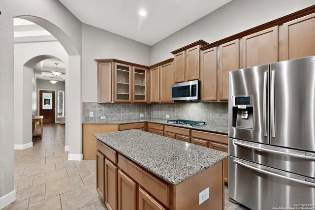a kitchen with stainless steel appliances granite countertop a refrigerator a stove and a sink with wooden floor