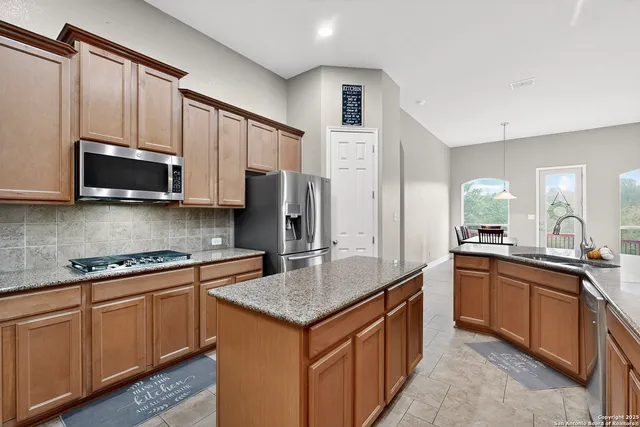 a kitchen with stainless steel appliances granite countertop a sink stove microwave and refrigerator