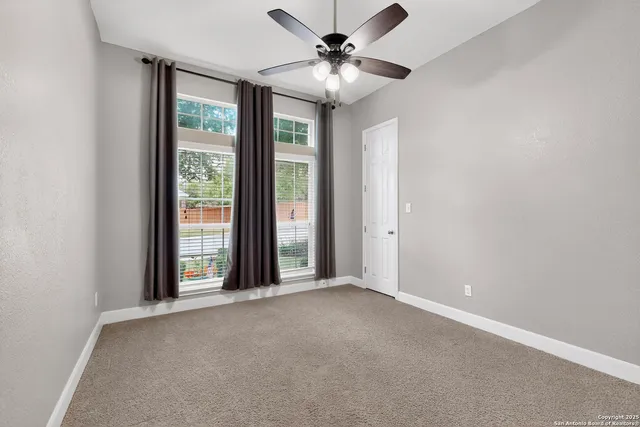 an empty room with windows and fan