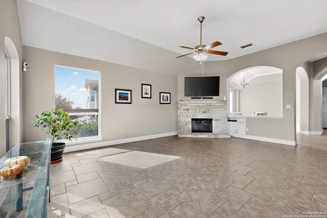 a view of a livingroom with a fireplace a chandelier and windows