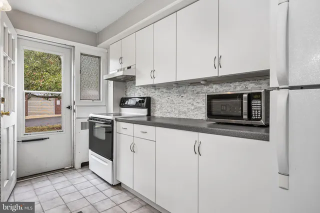 a kitchen with granite countertop white cabinets and white appliances