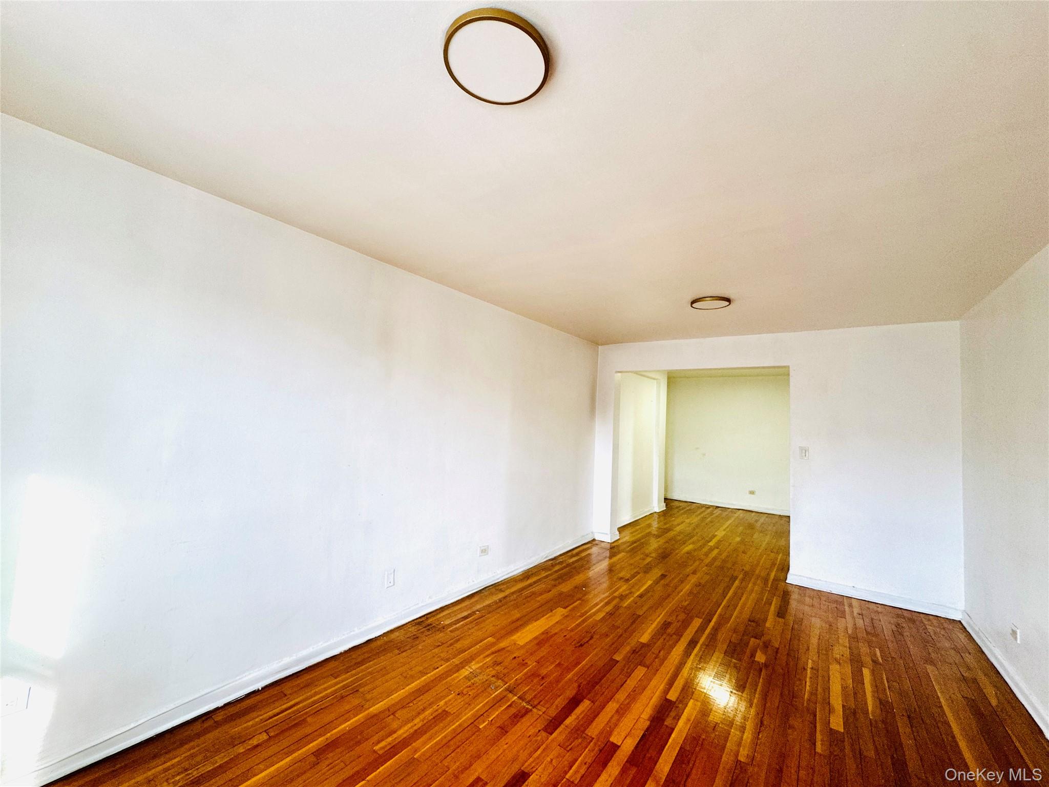 141-05 Pershing Crescent, Unit 207 Queens, NY 11435 - Photo 5 of 13 a view of a room with wooden floor and white walls