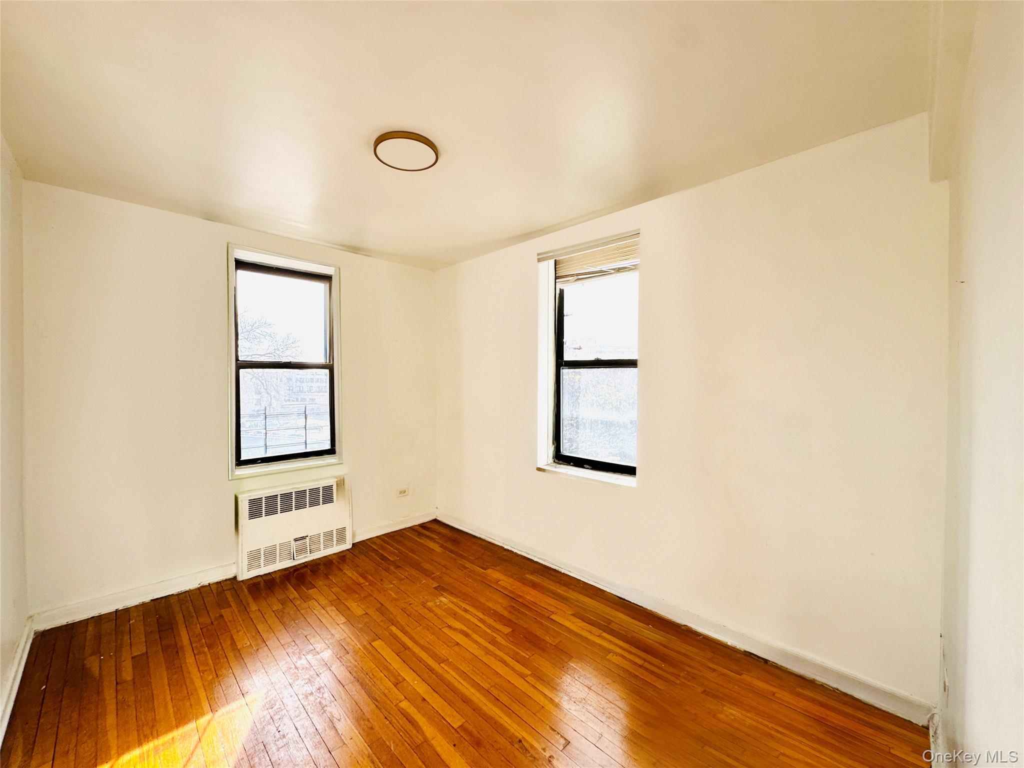 141-05 Pershing Crescent, Unit 207 Queens, NY 11435 - Photo 10 of 13 wooden floor in an empty room with a window