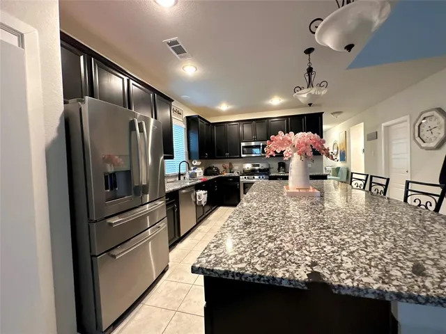 a large kitchen with a table and refrigerator