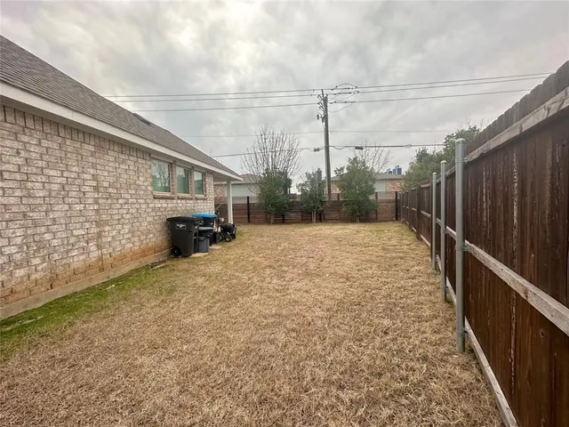 a backyard of a house with barbeque oven and wooden fence