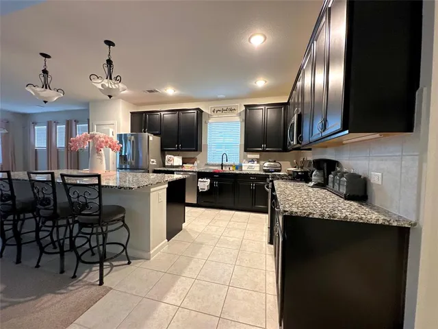 a large kitchen with kitchen island granite countertop a sink counter space cabinets and stainless steel appliances