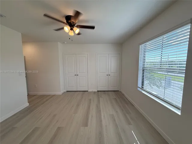 a view of empty room with wooden floor and fan