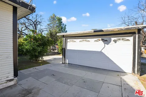a view of backyard with a small cabin and potted plants