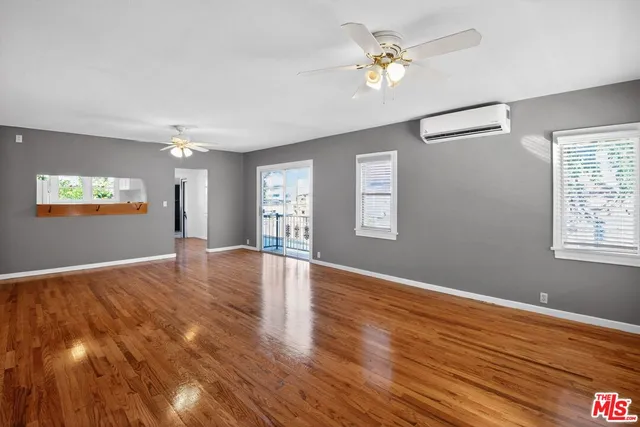 a view of an empty room with window and wooden floor