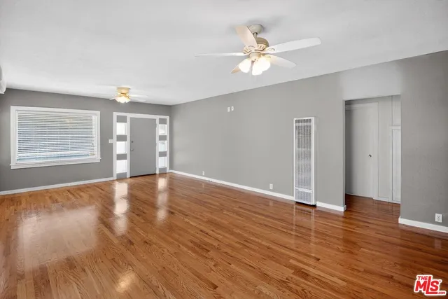 a view of an empty room with wooden floor and window
