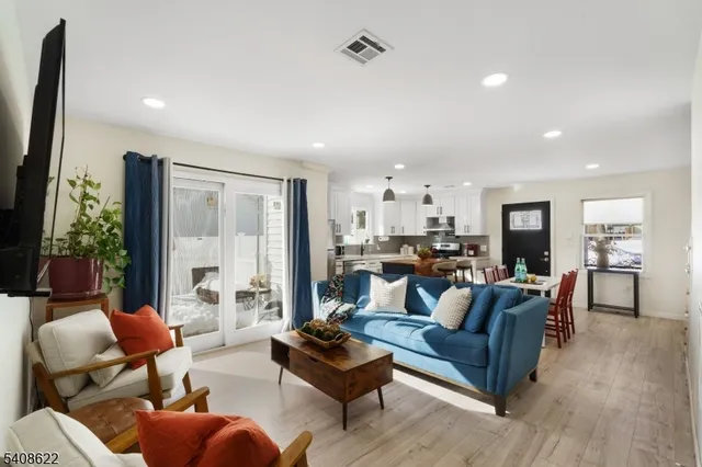 a living room with furniture kitchen view and a large window