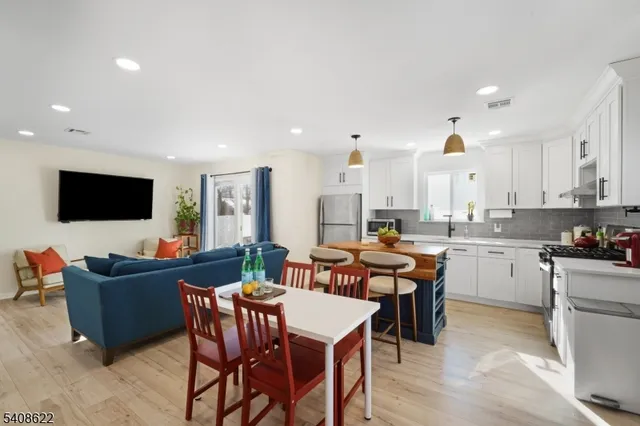 a open dining room with stainless steel appliances kitchen island granite countertop a table chairs and a refrigerator