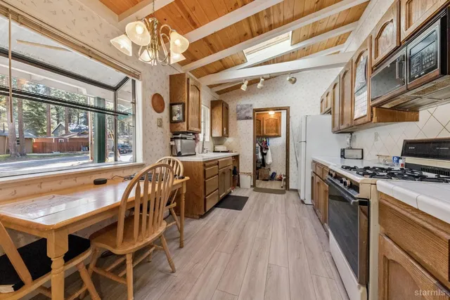 a kitchen with stainless steel appliances granite countertop a stove top oven a sink dishwasher a dining table and chairs with wooden floor