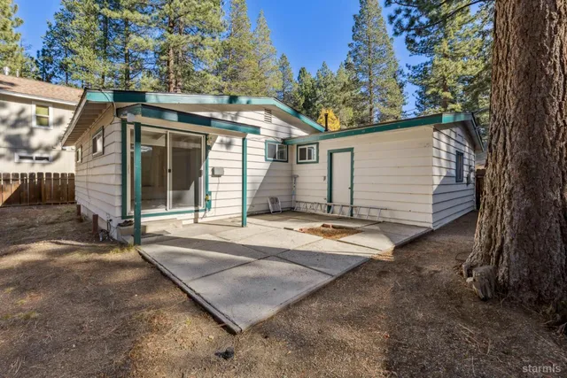 a view of a white house with a large tree and wooden fence