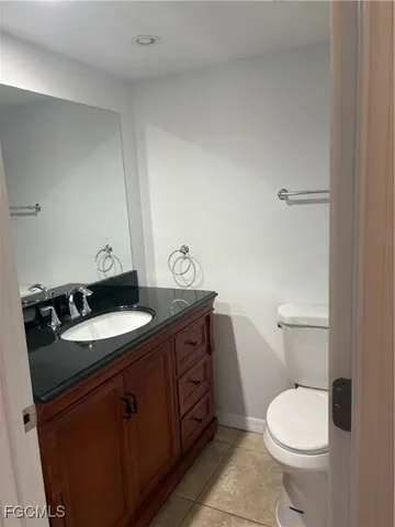 a bathroom with a granite countertop toilet sink and mirror