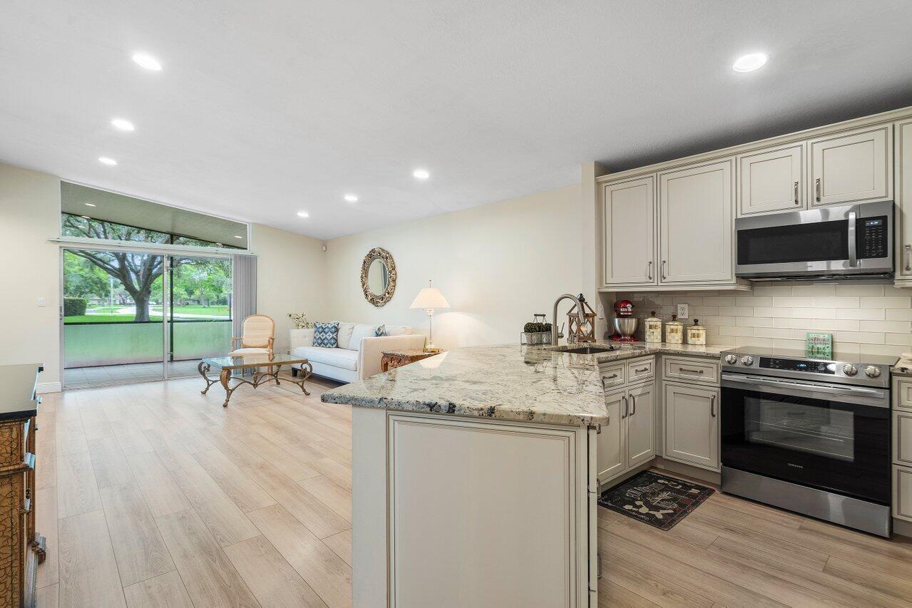 22543 Vistawood Way Boca Raton, FL 33428 - Photo 5 of 32 a open kitchen with stainless steel appliances granite countertop a stove a sink and a microwave