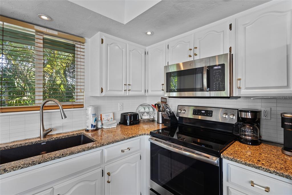 315 Spring Avenue Anna Maria, FL 34216 - Photo 19 of 63 a kitchen with stainless steel appliances granite countertop a sink a stove and a microwave
