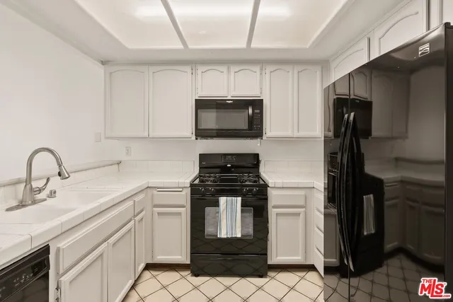 a kitchen with granite countertop a stove sink and refrigerator