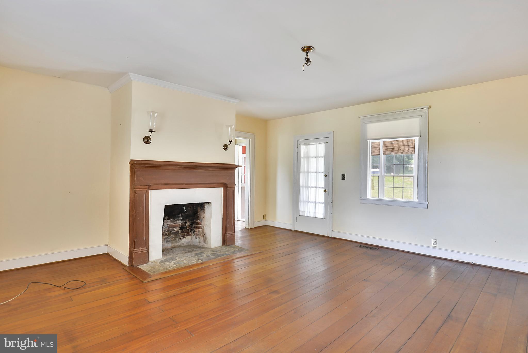 20852 St Louis Road Middleburg, VA 20117 - Photo 10 of 29 a view of an empty room with wooden floor fireplace and a window