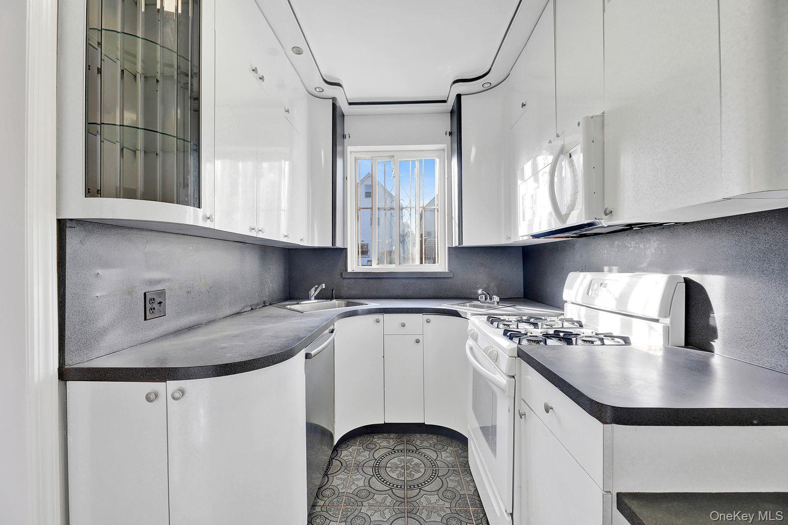 102-12 62nd Road Queens, NY 11375 - Photo 9 of 27 a kitchen with granite countertop a sink a stove and cabinets