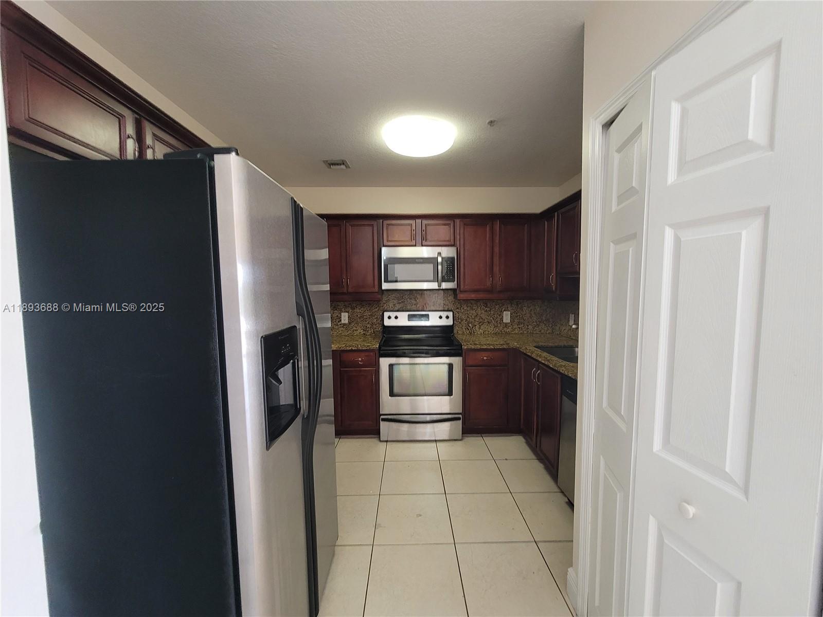 5271 Southwest 8th Street, Unit 411 Miami, FL 33134 - Photo 2 of 12 a kitchen with stainless steel appliances granite countertop a refrigerator and a stove top oven
