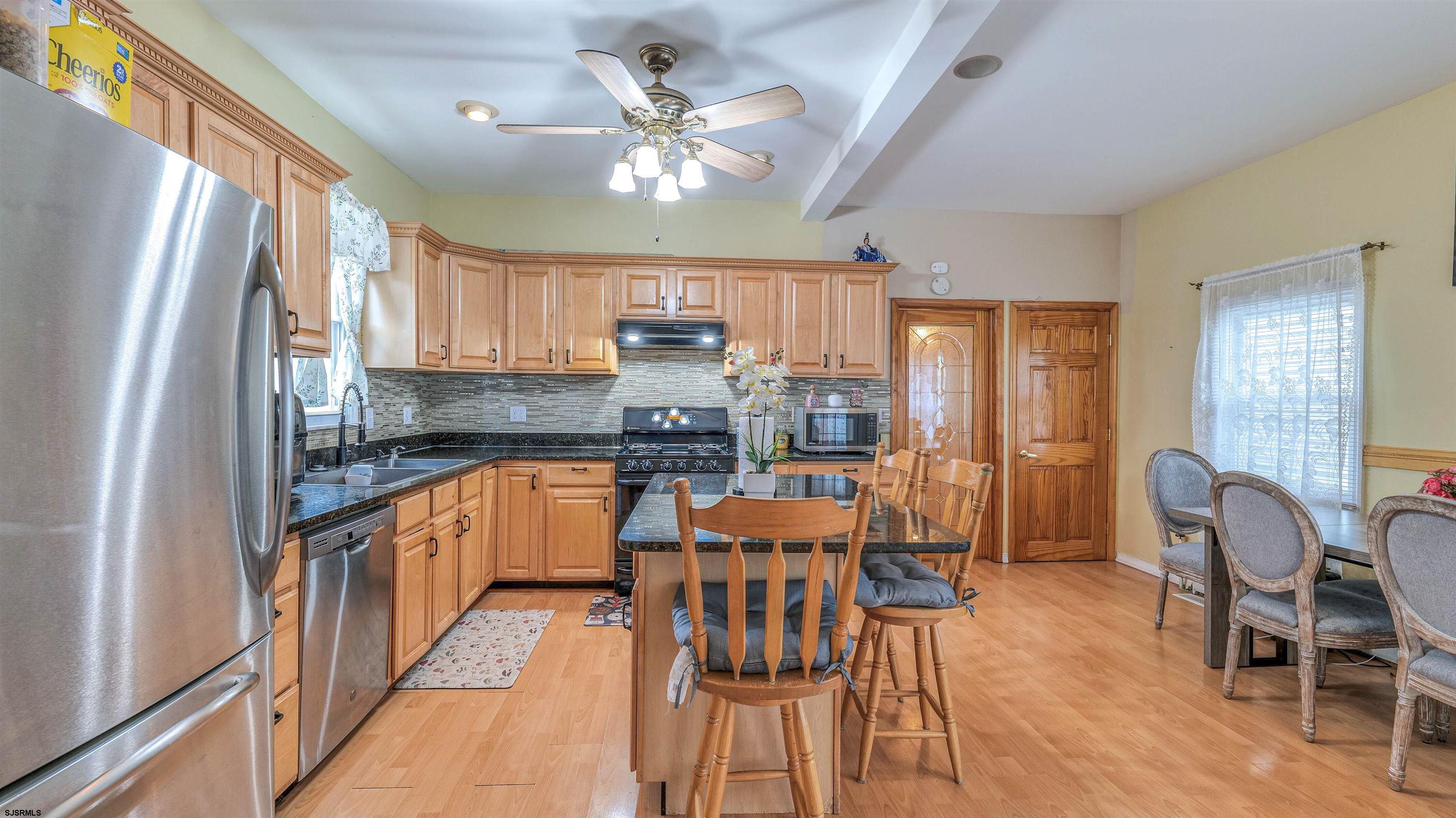 6015 Main Street Mays Landing, NJ 08330 - Photo 17 of 42 a kitchen with stainless steel appliances granite countertop a stove top oven a refrigerator a dining table and chairs with wooden floor