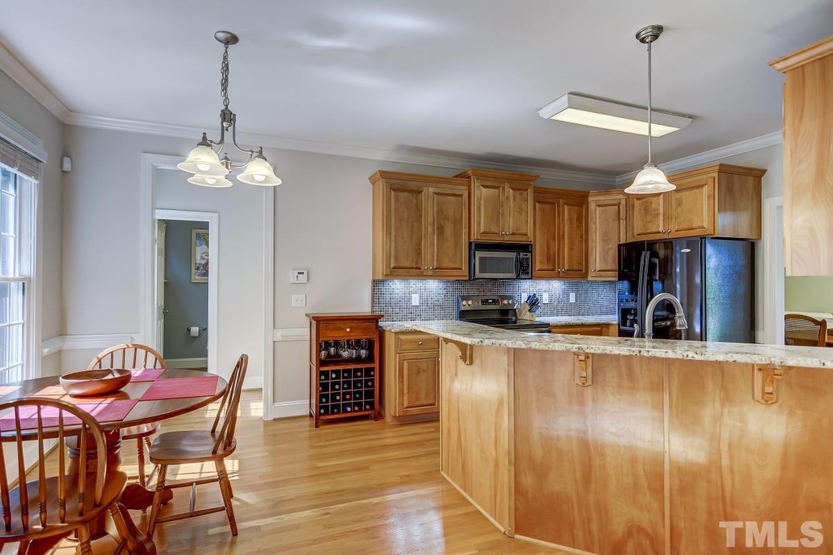7934 Pine Timber Drive Raleigh, NC 27613 - Photo 6 of 22 a kitchen with stainless steel appliances granite countertop a stove top oven a sink dishwasher a dining table and chairs with wooden floor