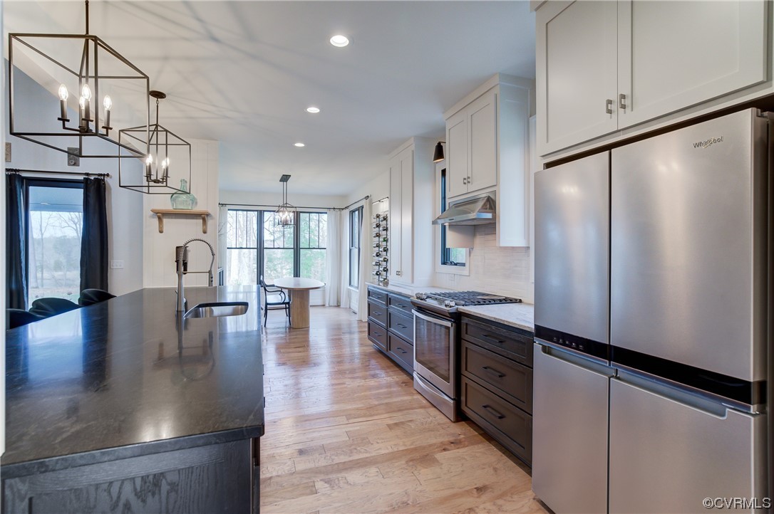 7097 Ware House Road Gloucester, VA 23061 - Photo 7 of 49 a kitchen with stainless steel appliances granite countertop a refrigerator a sink dishwasher a stove and a dining table with wooden floor