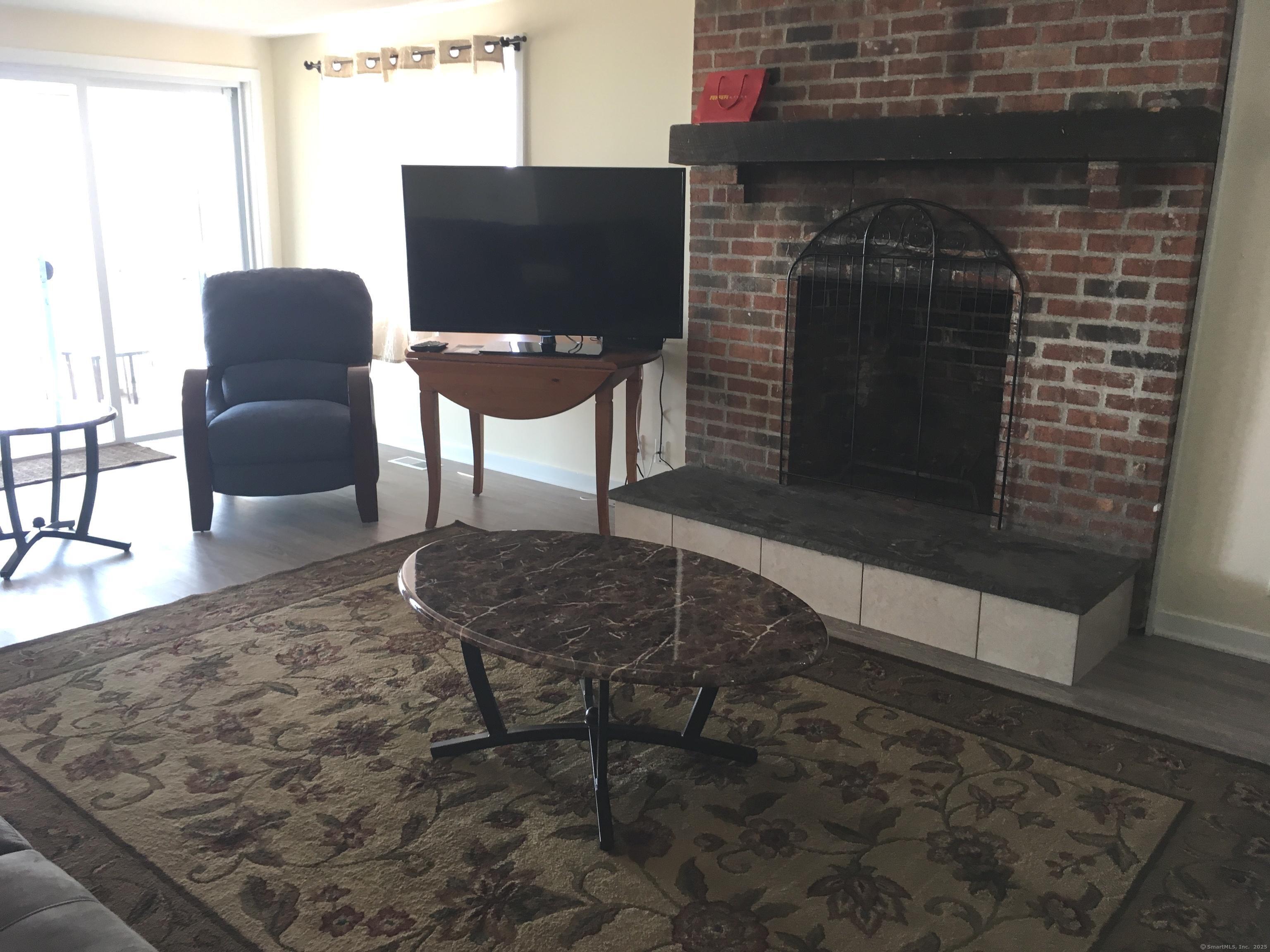 989 Fairfield Beach Road Fairfield, CT 06824 - Photo 15 of 27 a living room with furniture a fireplace and a flat screen tv